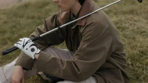 Young golfer sits calmly on the grass, practicing golf anger management